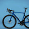 Blue road bike with aerodynamic design and carbon wheels, engineered for high-speed cycling.